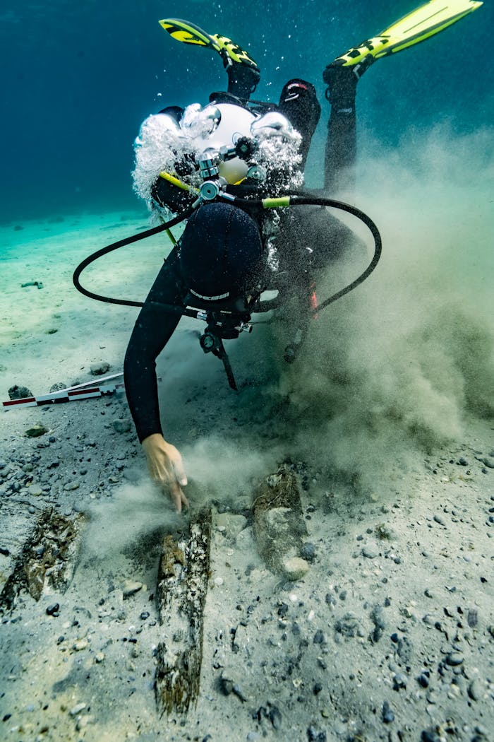gallery-4 A scuba diver inspects the seabed underwater in Croatia, surrounded by bubbles and sand.