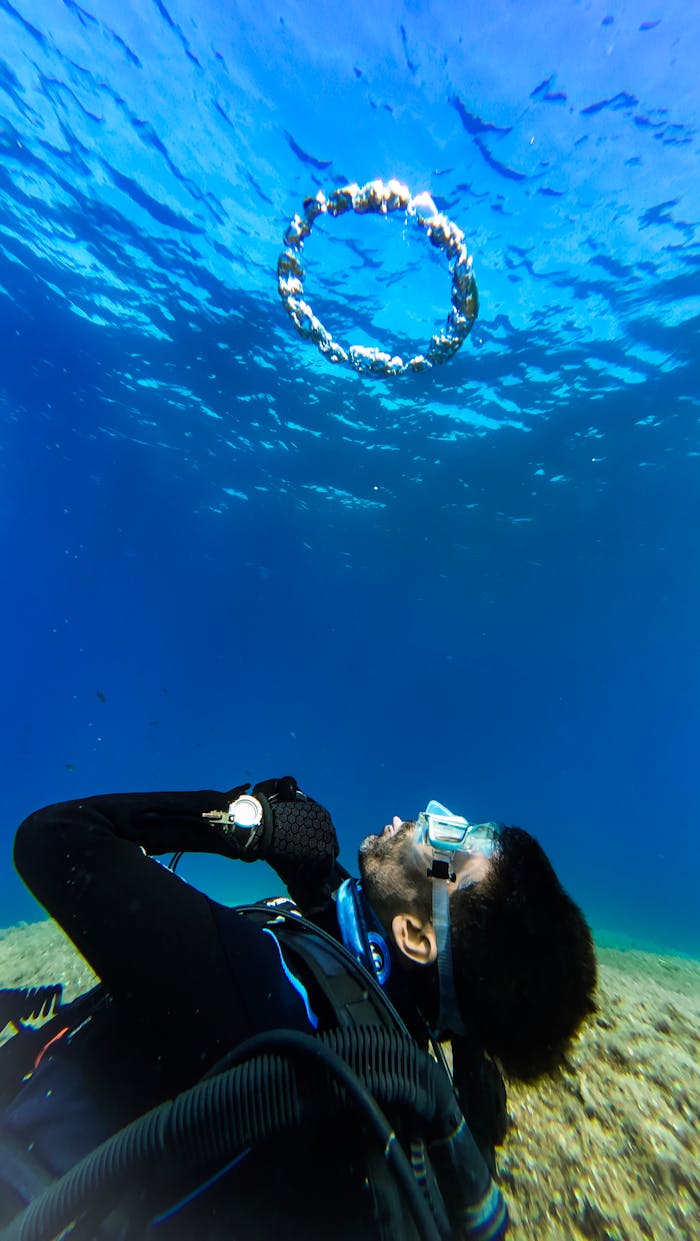 An underwater shot of a scuba diver creating a bubble ring in clear blue waters of Karaburun, Türkiye.